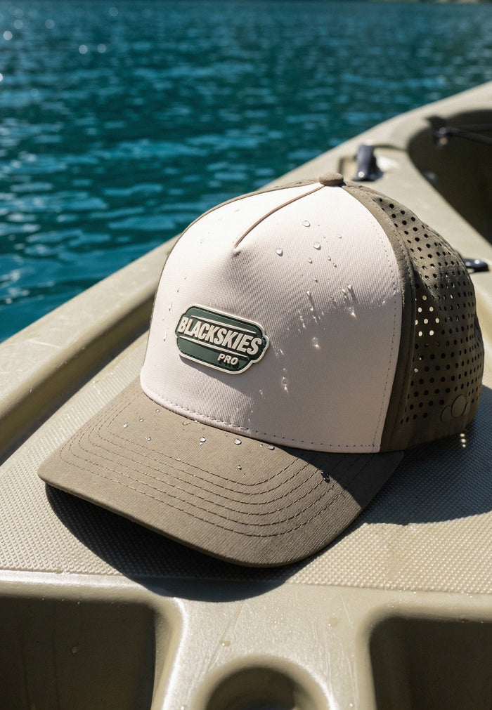Beige and brown cap with 'Blackskies Pro' logo on a kayak by a body of water