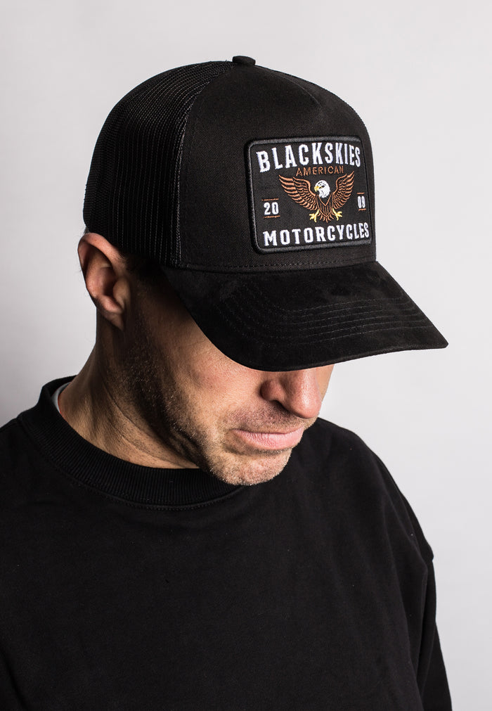 Person wearing a black cap with 'Blackskies Motorcycles' logo on a light gray background