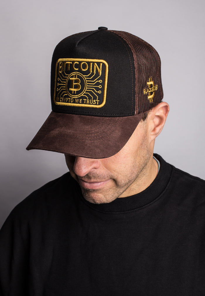Man wearing a black and brown cap with Bitcoin logo on a gray background