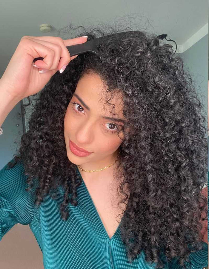 Woman with curly hair using detangling comb for styling