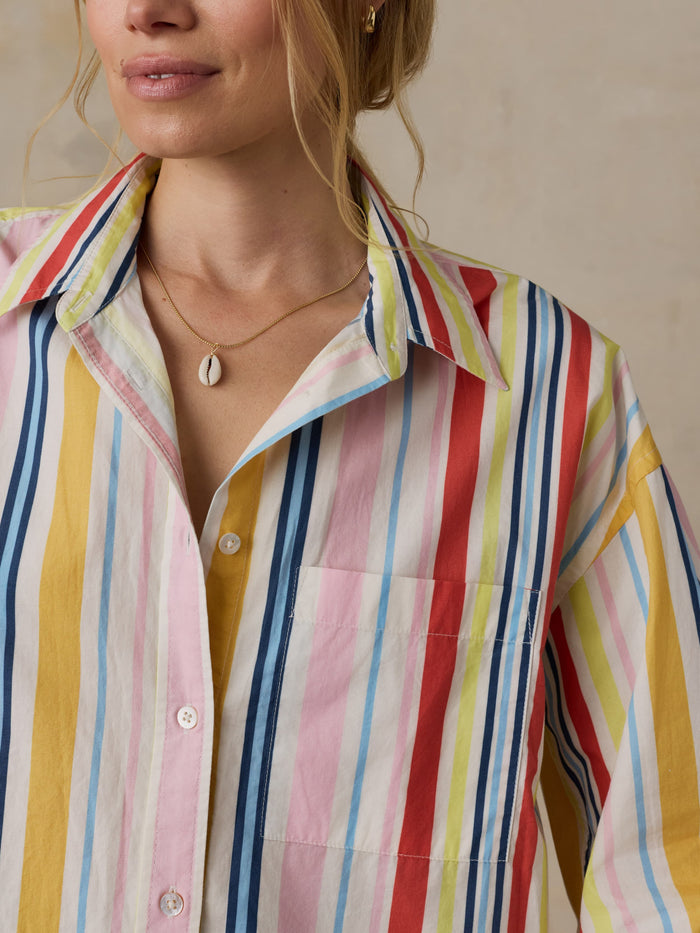 Close-up of a person wearing a colorful striped shirt with a neutral background
