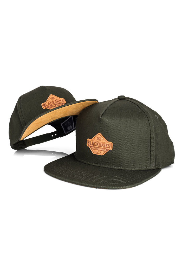 Two green caps with leather patches on a white background