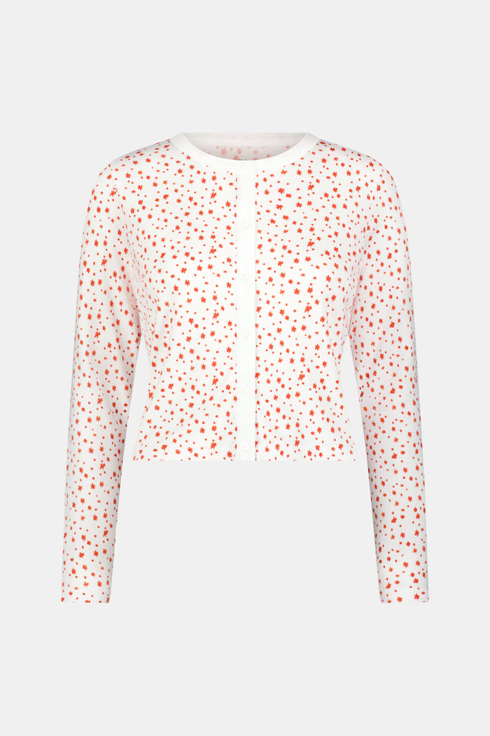 A woman wears the Roller Rabbit Étoiles Nessa Cardigan over a long-sleeve white pajama set with red polka dots, made from cozy Pima cotton in Peru, standing against a light background and looking at the camera with a relaxed expression.