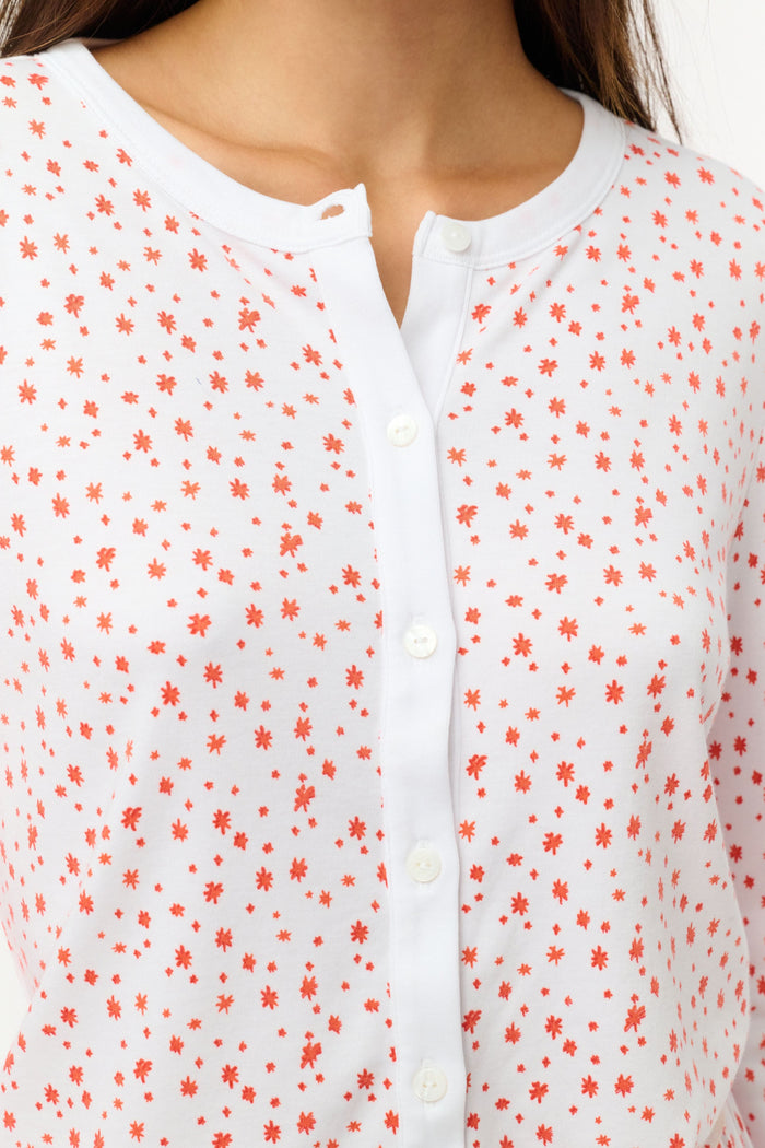 A woman wears the Roller Rabbit Étoiles Nessa Cardigan over a long-sleeve white pajama set with red polka dots, made from cozy Pima cotton in Peru, standing against a light background and looking at the camera with a relaxed expression.