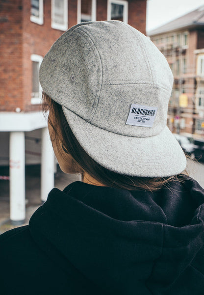 Person wearing a gray cap with a visible brand logo, standing outdoors.