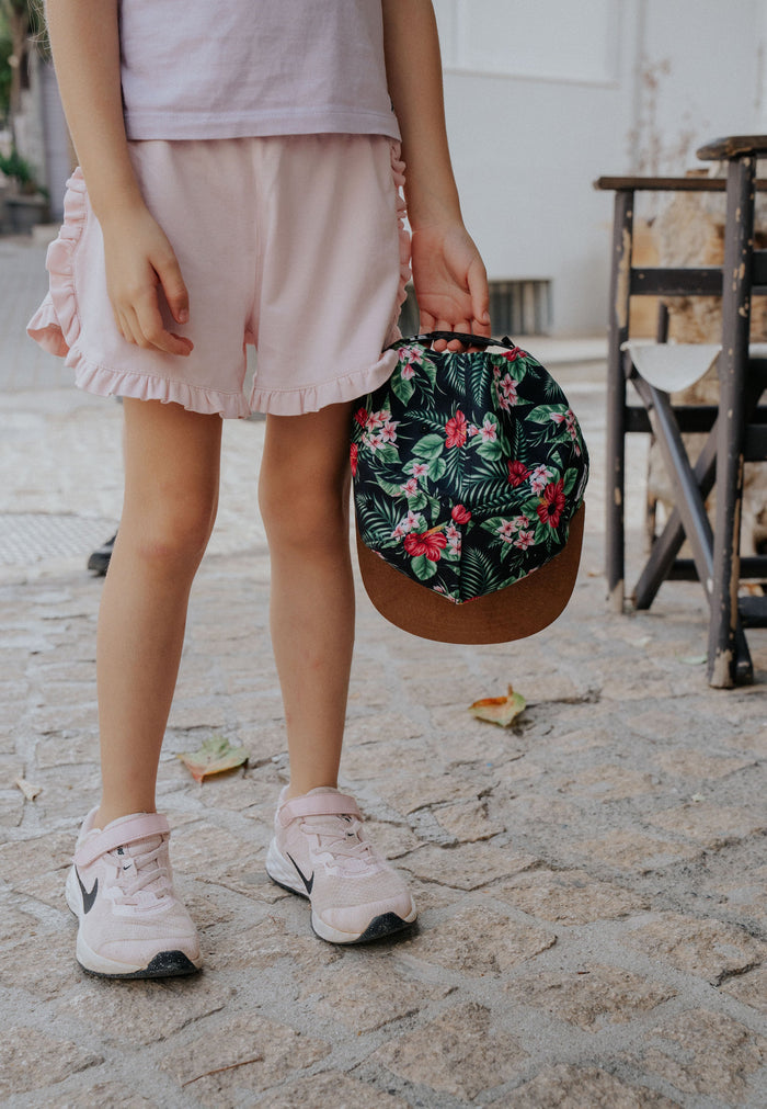Person holding a floral handbag on a stone pavement