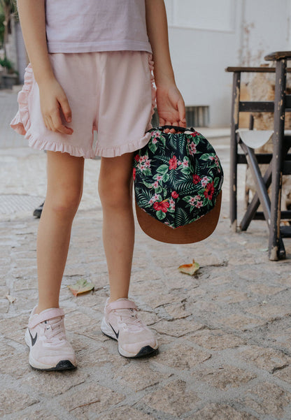 Person holding a floral handbag on a stone pavement