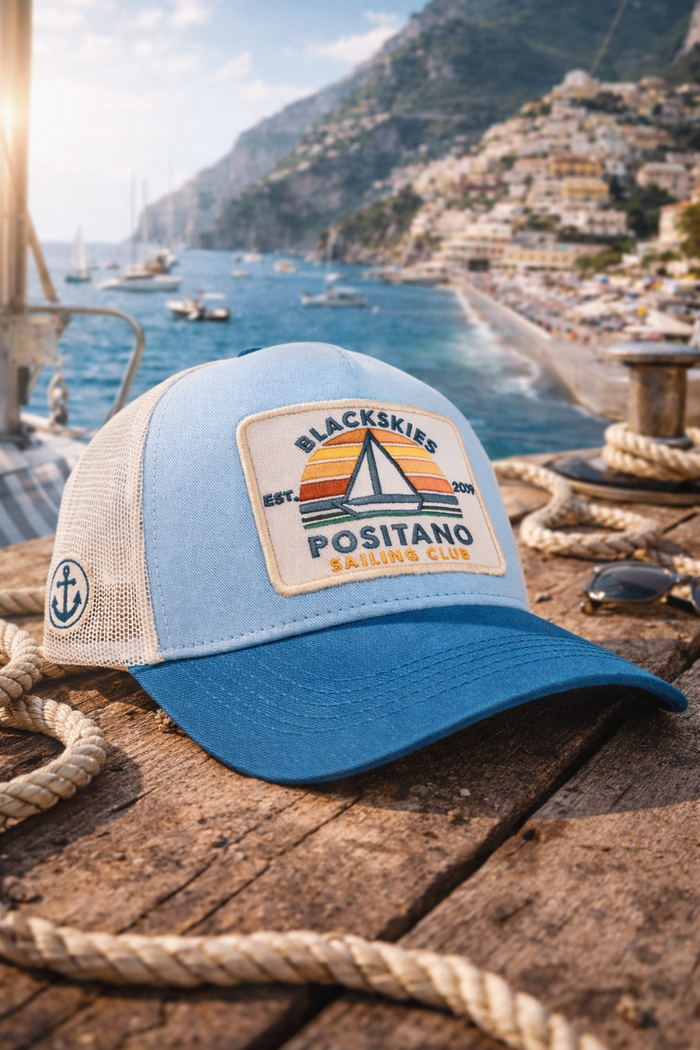 Blue and beige cap with a logo on a wooden surface with a scenic background