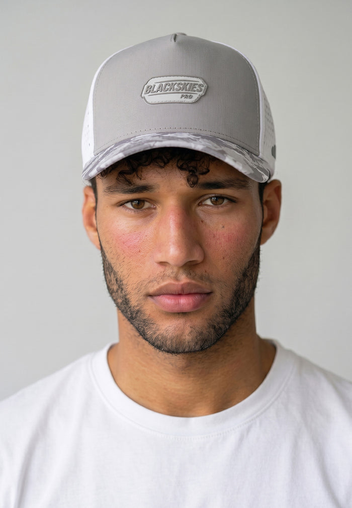 Man wearing a gray cap with a brand logo on a plain background