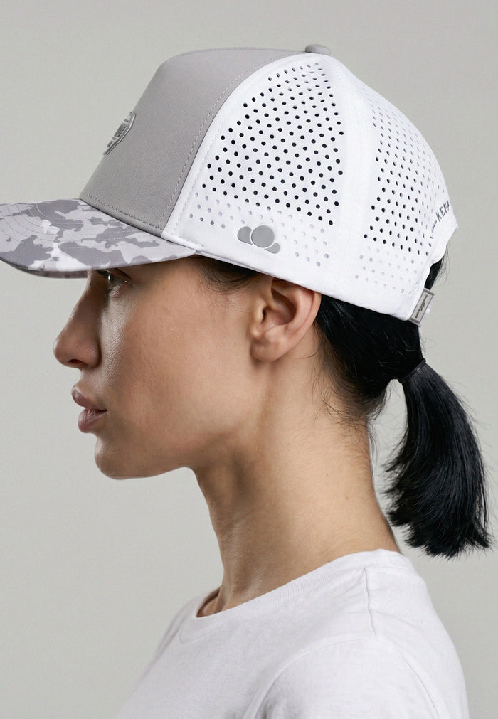 Person wearing a gray and white cap with a camouflage pattern on a light gray background