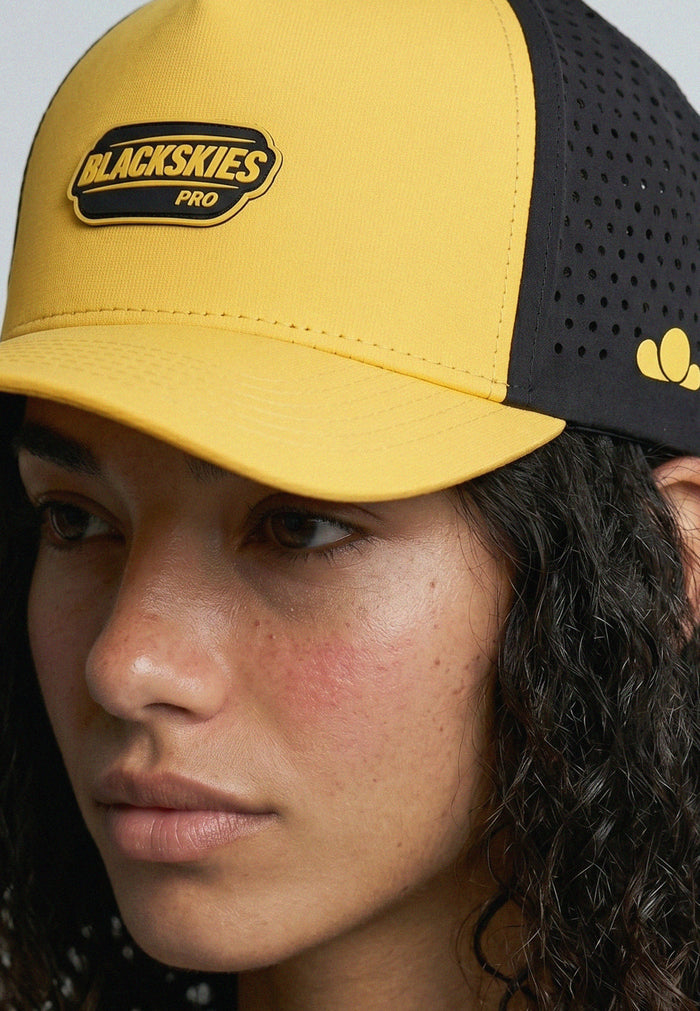 Person wearing a yellow and black cap with 'Blackskies Pro' logo