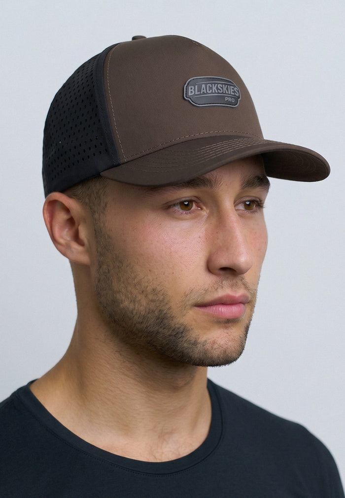 Man wearing a brown and black cap with 'Blackskies' logo on a light gray background