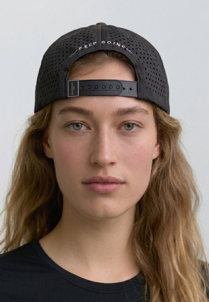 Person wearing a black cap with 'Keep Going' text on a plain background