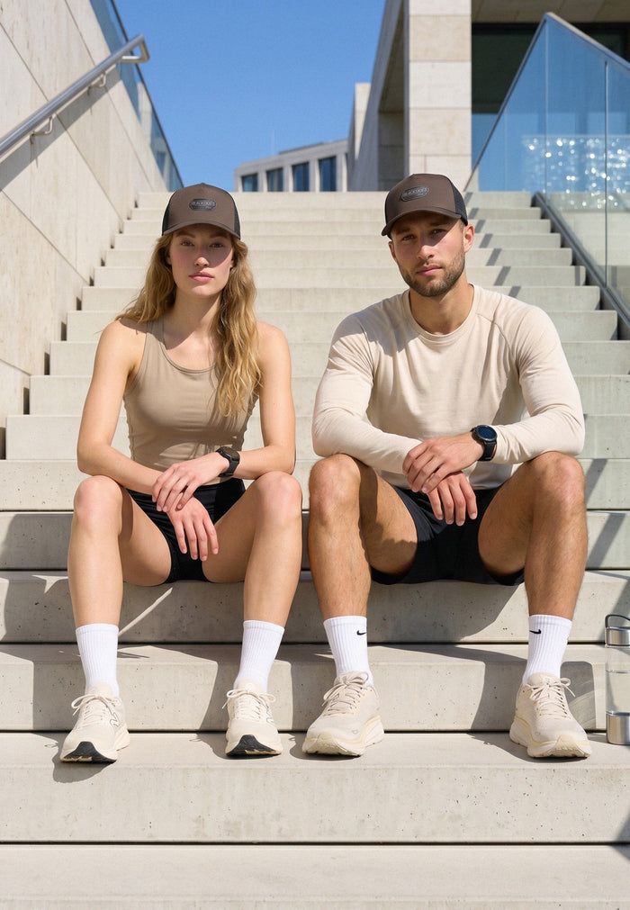 Two people sitting on steps wearing matching athletic outfits and hats.
