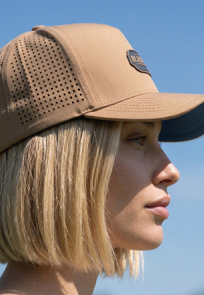 Person wearing a brown cap with a visible brand logo against a clear blue sky