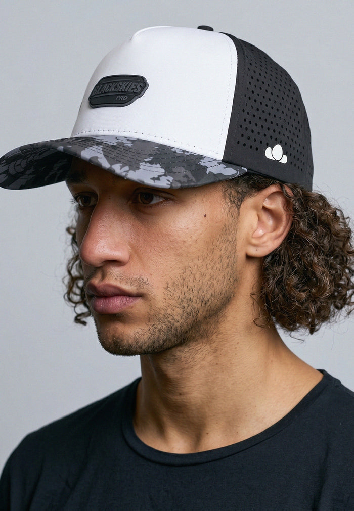 Man wearing a black and white cap with camouflage pattern on a gray background
