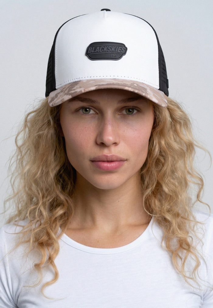Woman wearing a black and white cap with a visible brand logo on a plain background