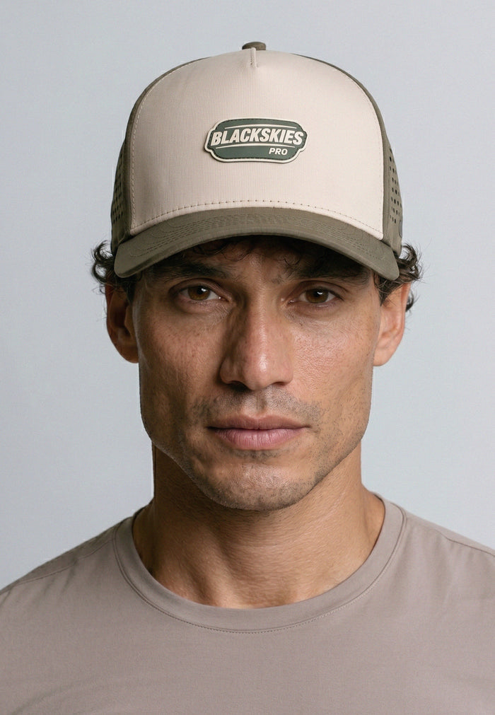 Man wearing a beige cap with 'Blackskies Pro' logo against a gray background