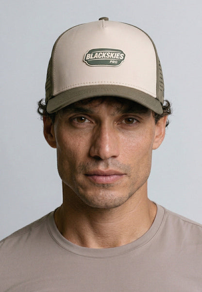 Man wearing a beige cap with 'Blackskies Pro' logo against a gray background