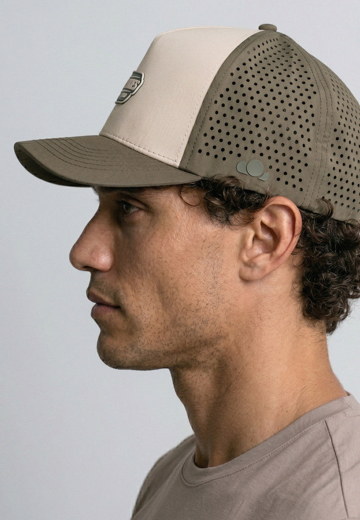Man wearing a beige and brown baseball cap against a plain background