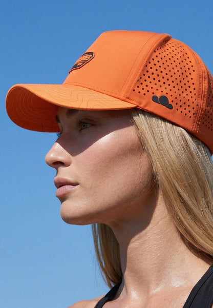 Woman wearing an orange cap against a clear blue sky