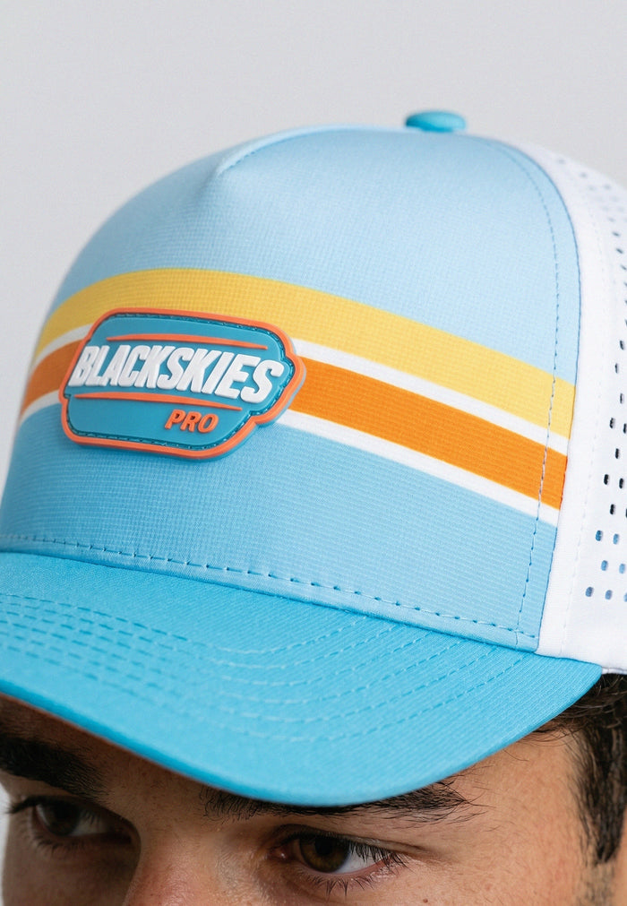 Blue cap with colorful stripes and 'BLACKSKIES PRO' logo on a gray background