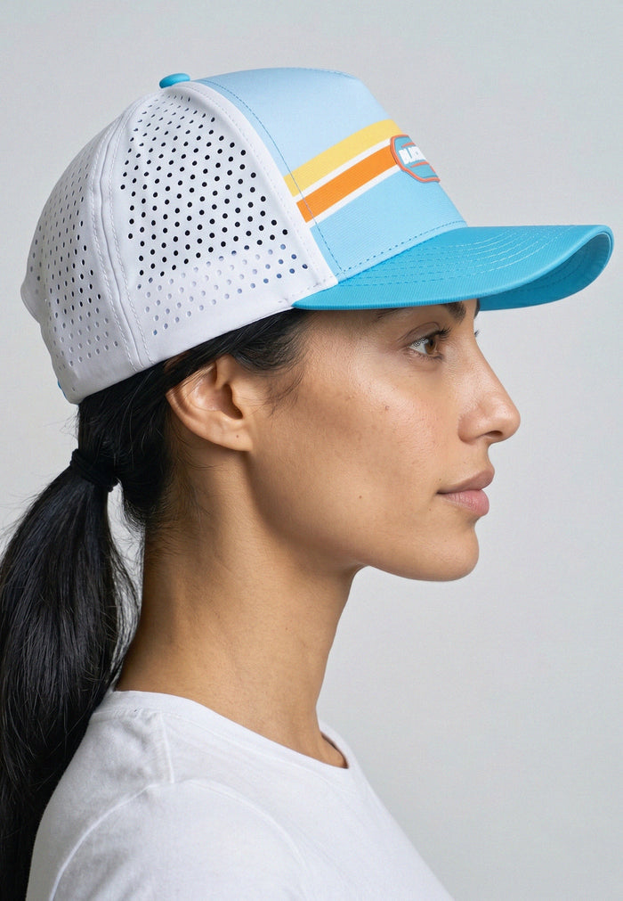 Woman wearing a white and blue cap with colorful accents on a gray background