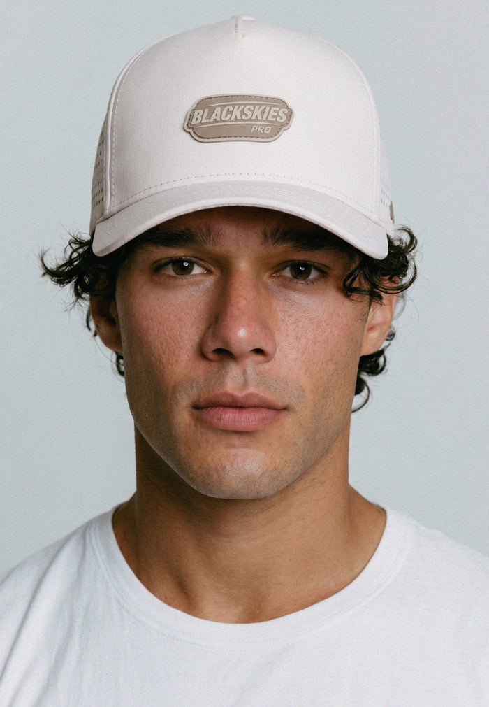 Man wearing a beige cap with 'Blackskies' logo on a light gray background