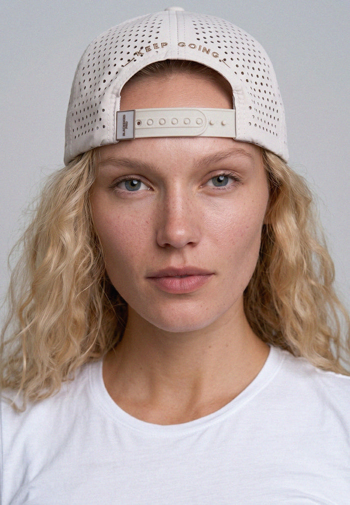 Person wearing a beige cap with text on a plain background
