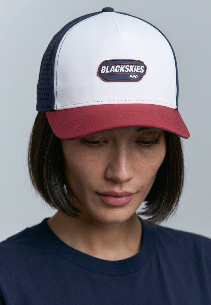 Person wearing a white and red cap with 'Blackskies' logo on a gray background
