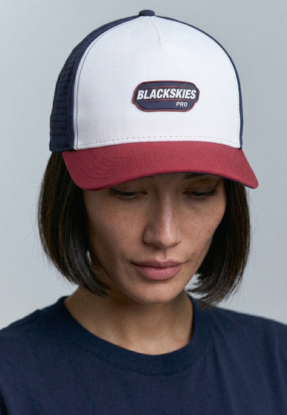 Person wearing a white and red cap with 'Blackskies' logo on a gray background