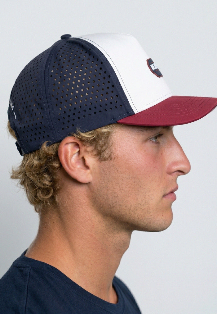 Man wearing a navy and red baseball cap on a plain background