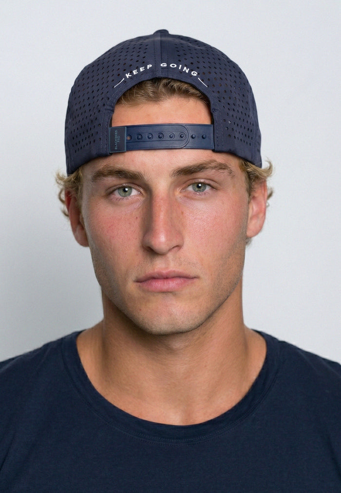 Man wearing a navy cap with 'keep going' text on a plain background