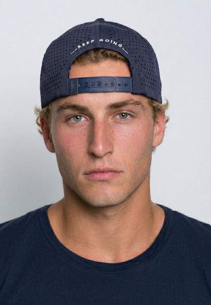 Man wearing a navy cap with 'keep going' text on a plain background