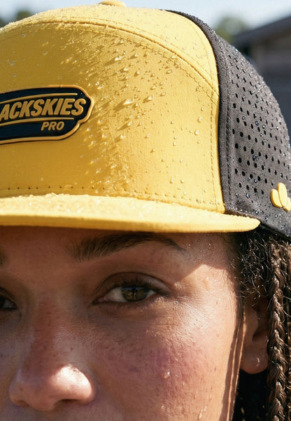 Person wearing a yellow and black cap with 'Backskies Pro' branding.