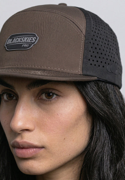 Person wearing a brown and black cap with 'Blackskies Pro' logo on a gray background