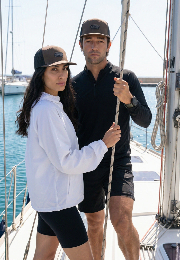 Two people on a sailboat with water and sky in the background