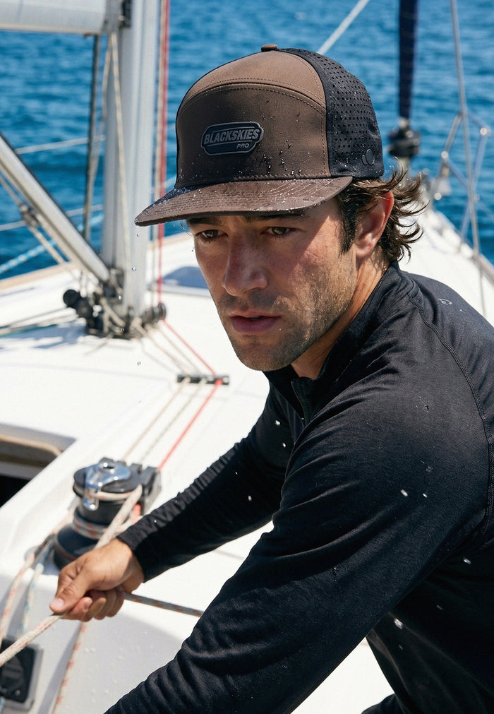 Man on a sailboat wearing a cap with a visible brand logo