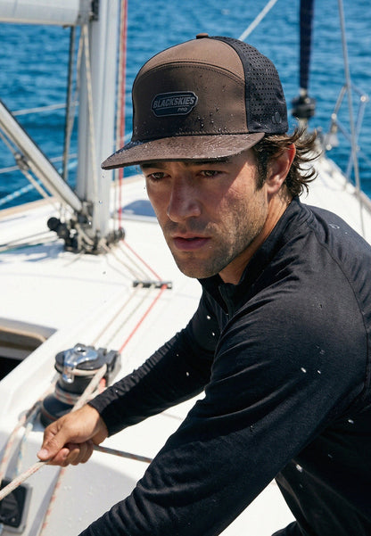Man on a sailboat wearing a cap with a visible brand logo