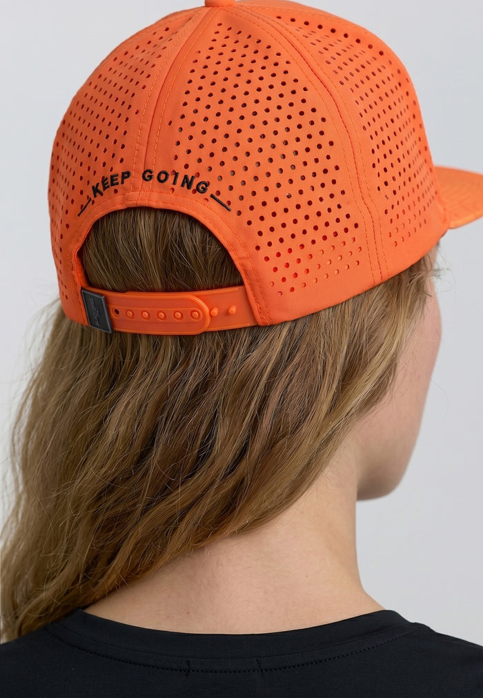 Orange cap with 'KEEP GOING' text worn by a person on a plain background
