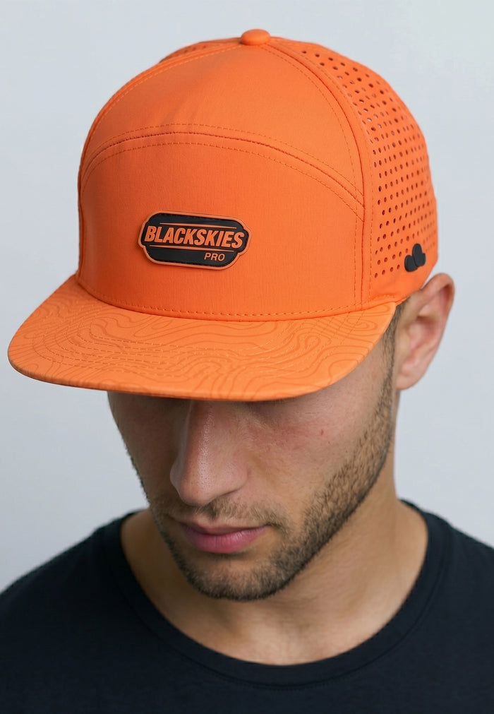 Person wearing an orange cap with a visible brand logo on a plain background