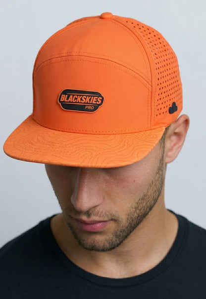 Person wearing an orange cap with a visible brand logo on a plain background