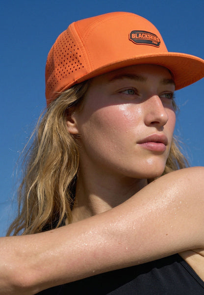 Person wearing an orange cap with 'Blackbeard' branding against a clear blue sky.