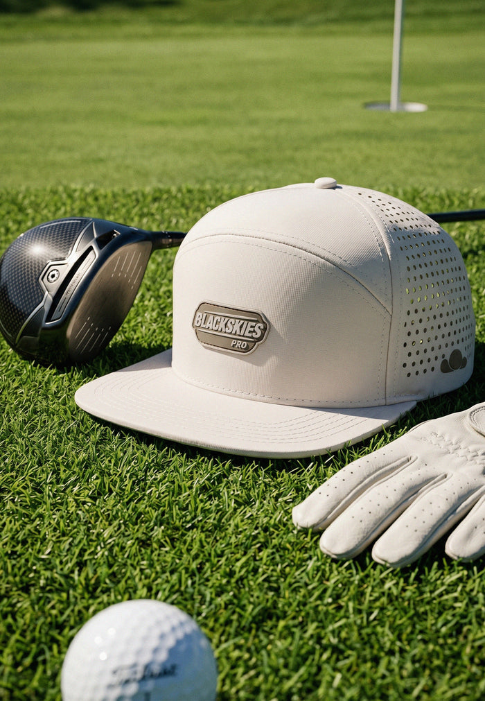 Golf hat, club, glove, and ball on a grassy surface with Blackskies Pro branding.