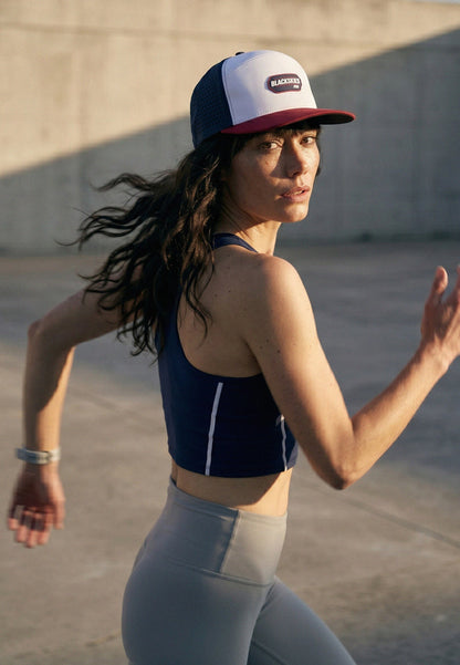 Woman running outdoors wearing a cap and athletic outfit.