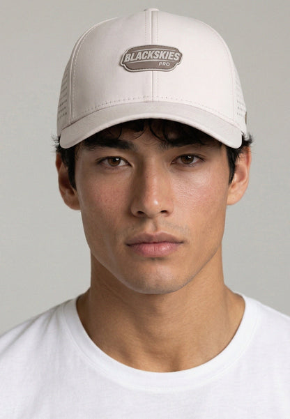 Man wearing a beige cap with 'Blackskies' logo on a gray background