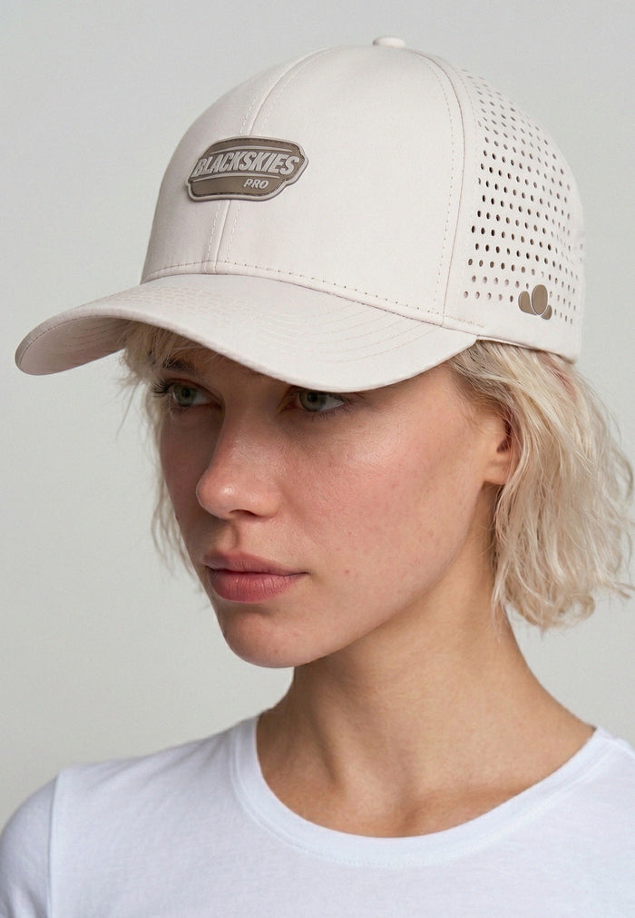 Person wearing a beige sport cap with a blackskies brand logo on a plain background