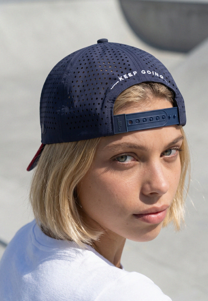 Person wearing a navy blue cap with 'Keep Going' text on a light background