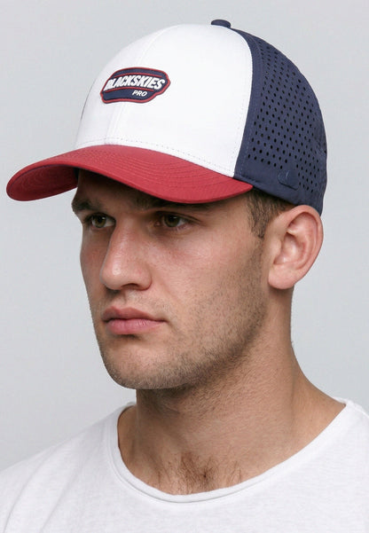 Man wearing a white, red, and navy baseball cap with a visible brand logo on a gray background