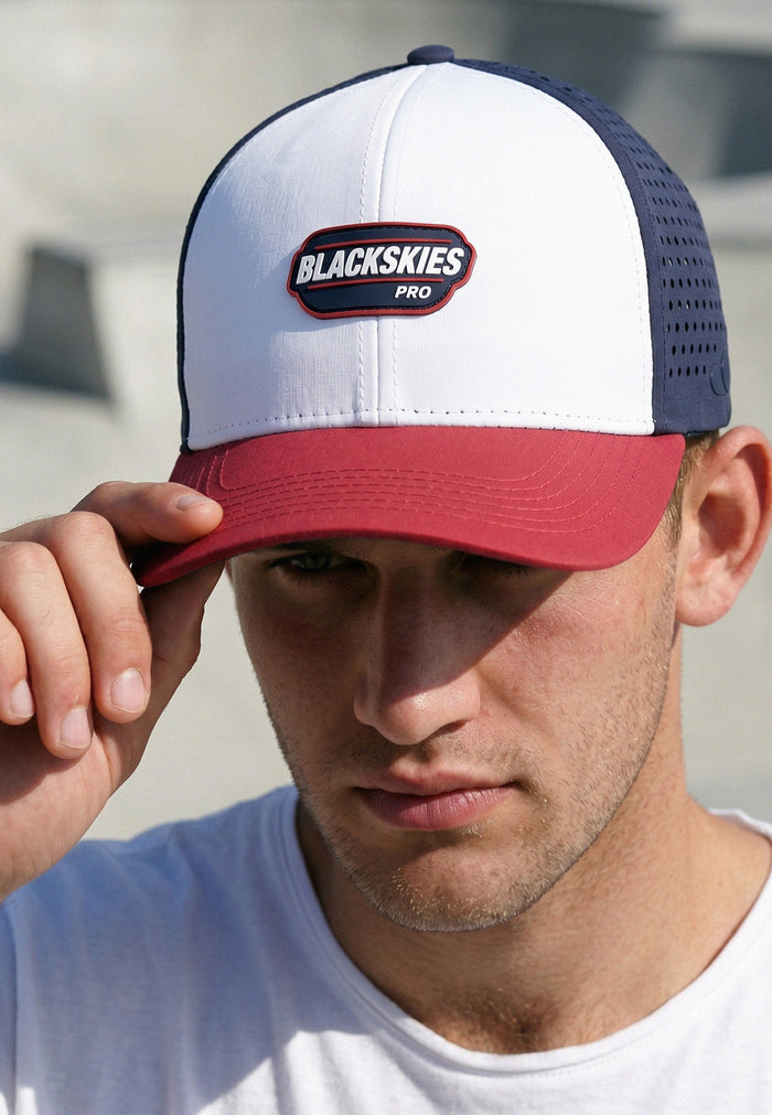 Person wearing a white and red cap with 'Blackskies Pro' logo, outdoors.